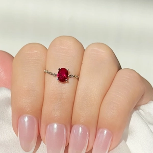 Detailed shot of an oval red zircon ring with gold plating and chain-style band on silk