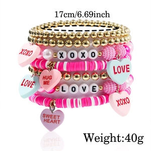 Detail of pink and gold stacked bracelets with XOXO, LOVE, and HUG ME letter beads