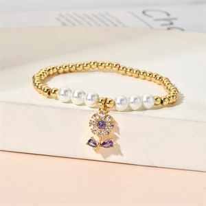 Detail of beaded bracelet with white pearls, gold beads, and a purple zircon flower charm