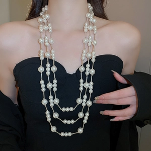 Close-up of layered pearl necklace with silver links on elegant black attire