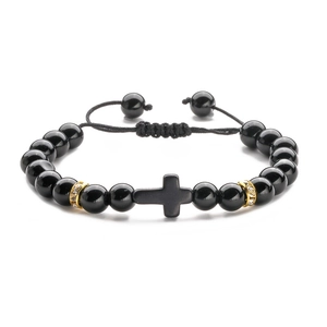 Macro view of black volcanic stone beads and a matte cross pendant with gold rhinestone accents