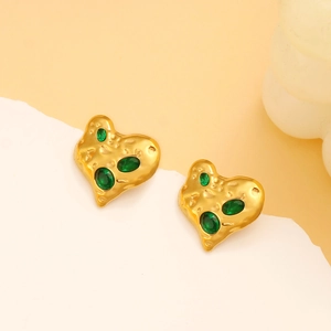 Close-up of vintage heart earrings with green oval gemstones on a golden finish