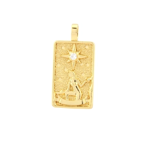 Macro detail of gold-plated tarot card pendant with embossed figure and star
