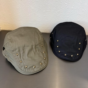 Close-up of military green and black newsboy caps with vintage metal rivet details