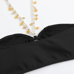 Dettaglio del bikini con stelle marine dorate, perle e ciondoli a forma di conchiglia
