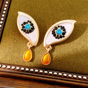 Close-up of vintage eye-shaped drop earrings with enamel finish and crystal details