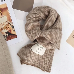Détail de l'écharpe en maille chevron marron clair avec étiquette tissée minimaliste