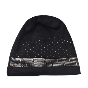 Detailed macro shot of black knit beanie with sapphire rhinestones and metal rivets decoration