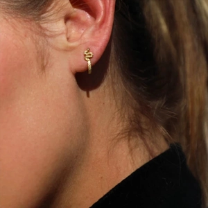 Detail showing a golden snake wrap earring featuring textured scales on earlobe