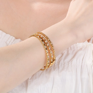 Dettaglio di tre braccialetti in acciaio inossidabile placcato oro 18K con zirconi bianchi