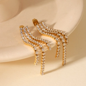 Macro shot of gold tassel earrings with triple row zircon inlay on a ceramic surface
