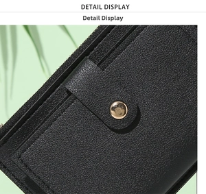 Macro view of black litchi grain leather wallet featuring gold snap and zipper details