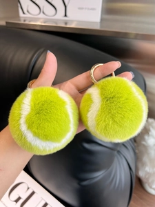 Macro view of plush faux fur tennis ball keychains with polished gold hardware