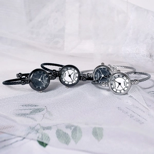 Detail of four quartz bangle watches with Roman numerals on white lace fabric