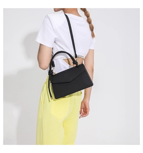 Model wearing a black vertical textured PU leather crossbody bag with knot handle detail