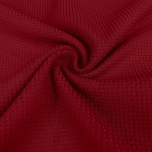 Macro shot of dark red waffle textured fabric showing honeycomb weave and soft drape