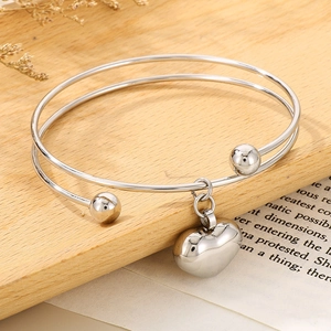 Silver heart pendant double-loop bangle with spherical ends on a decorative wooden background