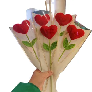 Handmade crochet heart bouquet with five red knitted flowers and green stems in gift wrap