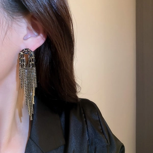Macro shot of long black tassel earrings with golden base and sparkling faceted beads