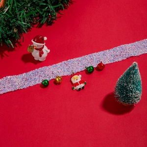 Detail of Christmas lace collar with Santa pendant and colorful bells on red background