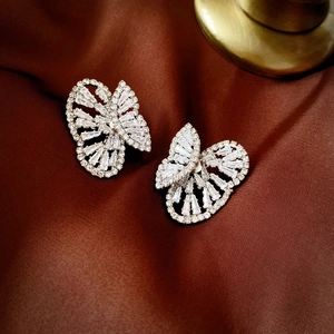 Sparkling zircon butterfly stud earrings in silver on brown satin background