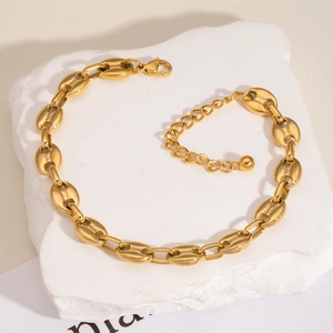 Elegant gold pig nose link anklet in stainless steel displayed on a natural stone base