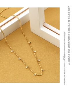 Detail of gold plated bead necklace with sparkling bezel set zircon stone pendants