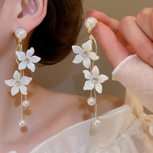 Detail of long floral drop earrings with white petals, pearls and sparkling rhinestones