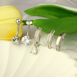 Set of five silver stainless steel belly rings with clear cubic zirconia on a white shell