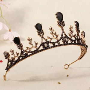 Detail of vintage gold crown featuring ornate leaf textures and black teardrop gemstones