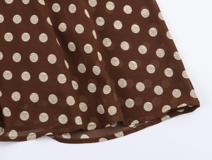 Detail of elegant brown polka dot chiffon fabric with soft pleats and smooth texture