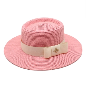 Pink wide brim boater straw hat featuring cream ribbon and golden bee ornament
