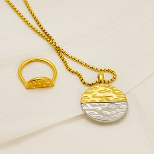 Detail of two-tone gold and silver necklace with hammered texture and matching ring