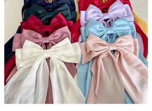 Detailed flat lay of colorful large satin bow hair clips with long ribbons in vibrant silk fabric