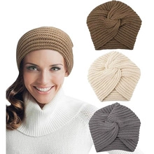 Detail of chunky cable knit patterns and warm pom-poms on various color winter beanies