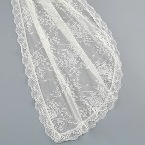 Close-up of elegant white floral lace fabric with intricate mesh patterns and scalloped edges