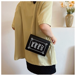 Lifestyle shot of a black book-shaped crossbody bag with Little Black Magic Book print