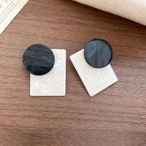 Detail view of square shell and wood bead earrings with marble texture on wooden surface