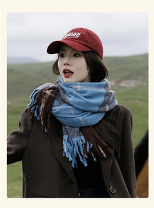 Close-up of blue and brown plaid scarf with tassels paired with a red baseball cap
