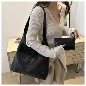 Detail of black woven leather texture on a large tote bag and matching inner pouch