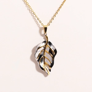 Detail of leaf pendant with gold and silver dual-tone finish on a golden chain necklace