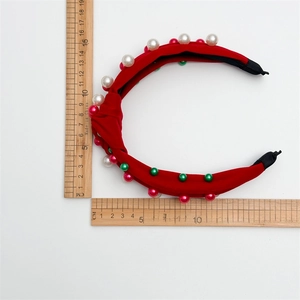 Détail du serre-tête en velours rouge avec perles et mesures sur fond blanc