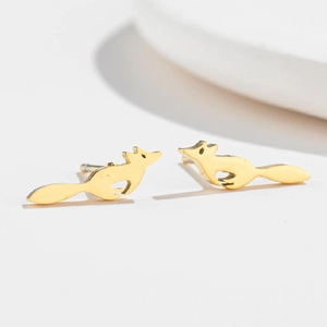 Macro detail of elegant golden running fox studs showing smooth polished metallic texture
