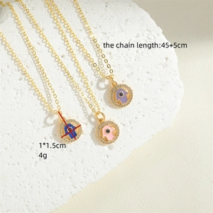 Golden Hamsa Hand necklaces with blue, pink, and purple pendants on a stone block