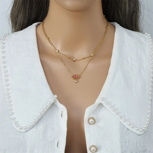 Double-layered gold necklace with pink lotus flower pendant worn by a model