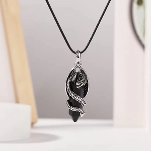Vue macro d'un pendentif dragon argenté entourant un cristal noir sur cordon ciré