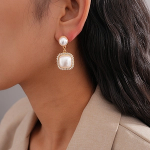 Detailed view of elegant pearl drop earrings with rhinestones on a female model