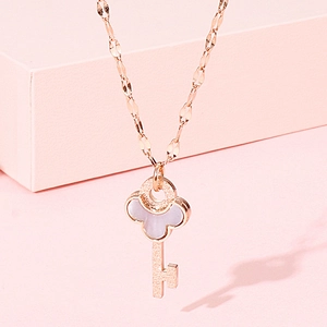 Macro detail of rose gold key pendant with shell inlay and twisted water wave chain