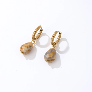 Macro view of gold hoop earrings with marble-textured teardrop stone pendants