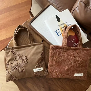 Retro camel suede handbag with floral embroidery on a rustic wooden table